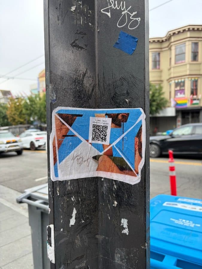 Dear Gay Stranger sticker on a scratched metal pole