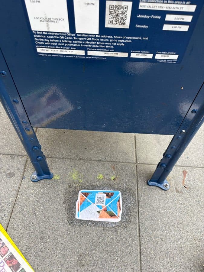 Dear Gay Stranger sticker on the sidewalk under a USPS mailbox